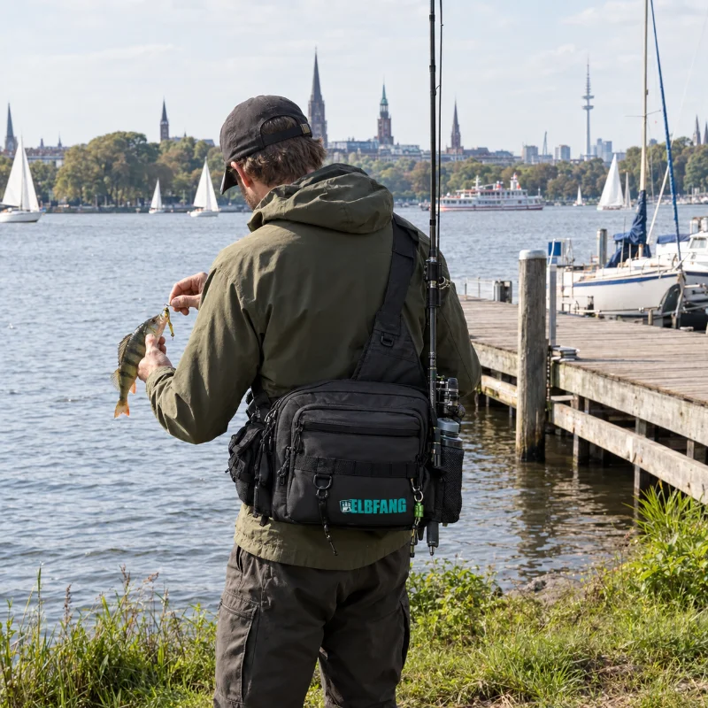 Streetfishing-Angler an der Hamburger Außenalster hakt einen Barsch ab, die Rute steckt im Rutenclip der ELBFANG Angeltasche